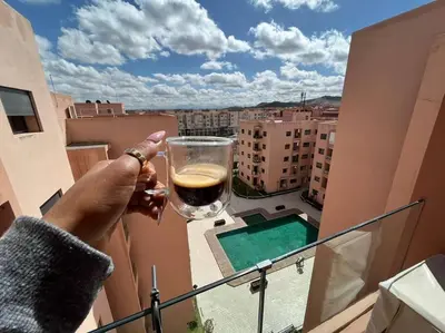 a person holding a glass of wine on a balcony at Lovely family condo in residence Marrakech in Marrakech