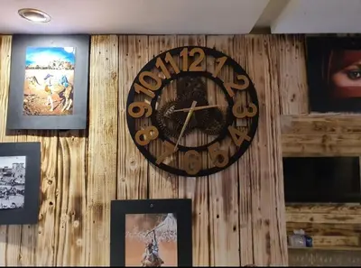 a clock hanging on a wooden wall with pictures at studio funny house près de la grande place jamaa el fna in Marrakech