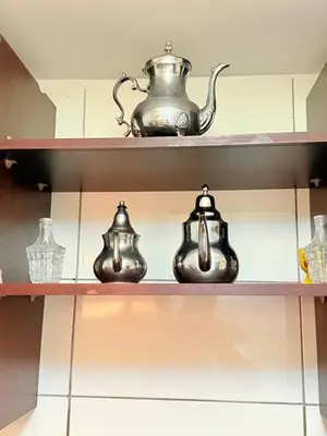 three tea pots and vases on a shelf at Appartement en résidence privée in Marrakech