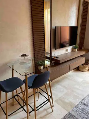 a living room with a glass table and a television at Duplex Cosy dans résidence avec piscine in Marrakech