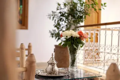 a table with a vase of flowers on a table at Riad Petite Rose in Marrakech