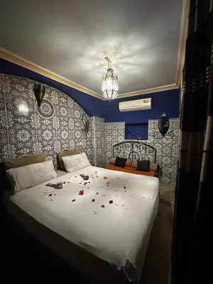 a bedroom with a white bed with red rose petals on it at riad dar saba shika in Marrakech