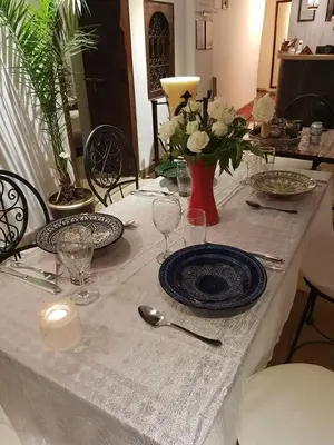 a table with plates and glasses and a vase with flowers at riad dar saba shika in Marrakech