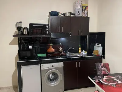 a kitchen with a washing machine and a microwave at 1er étage numéro 5 avec balcon POUR FAMILLE in Marrakech