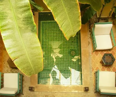 a view of a pool with two chairs and a banana leaf at RIAD DAR NAOMI in Marrakech
