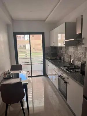 a kitchen with white cabinets and a table with chairs at Appartement résidence Marrakech haut standing piscine in Marrakech