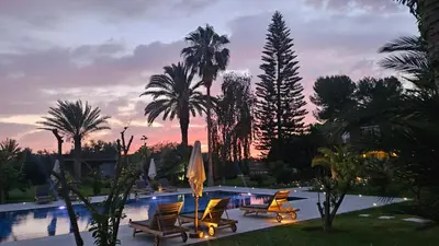 a pool with chairs and a umbrella and palm trees at Villa Fima Kech in Marrakech