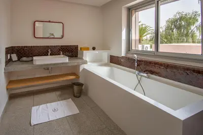 a bathroom with a tub and a sink and a window at Villa Fima Kech in Marrakech