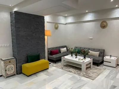 a living room with couches and a table and a yellow chair at Appartement en Duplex avec 3 chambres Haut Standing Gueliz Marrakech in Marrakech