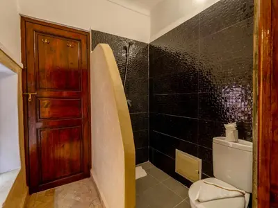 a bathroom with a toilet and a wooden door at Riad Zehar 79 & Spa in Marrakech