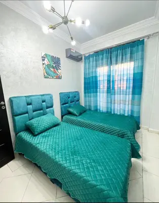 a bedroom with a bed with a green comforter at Nice new apartment in the city center in Marrakech