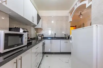 a kitchen with white cabinets and a white refrigerator at Appartement 2 chambres in Marrakech