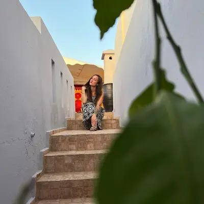 a woman sitting on the stairs of a building at Riad Pourpre Medina in Marrakech