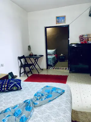 a room with two beds and a table and a doorway at Calm appartment close to airport of Marrakech in Marrakech