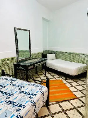 a room with two beds and a mirror at Dar jamaa lfna in Marrakech