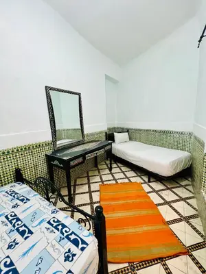 a room with two beds and a mirror and a chair at Dar jamaa lfna in Marrakech