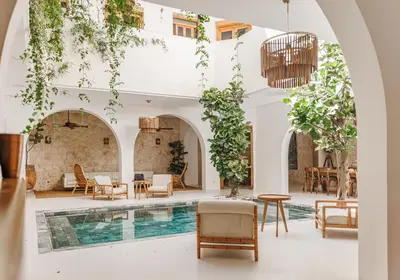 a hotel lobby with a pool and tables and chairs at Pure House Marrakech in Marrakech