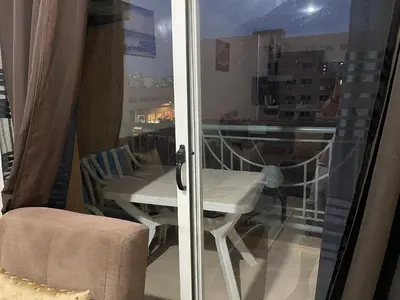 a room with a balcony with a table and a window at Appartement 17 3ème étage avec balcon POUR FAMILLE in Marrakech
