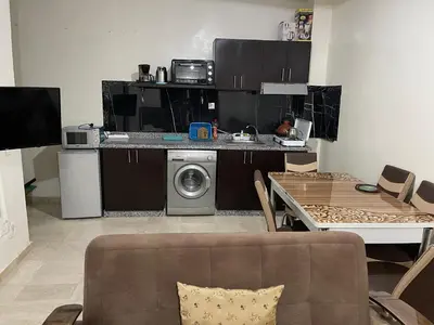 a living room with a table and a kitchen at Appartement 17 3ème étage avec balcon POUR FAMILLE in Marrakech