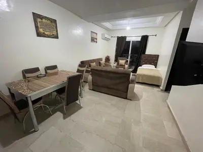 a living room with a couch and a table and chairs at Appartement 17 3ème étage avec balcon POUR FAMILLE in Marrakech