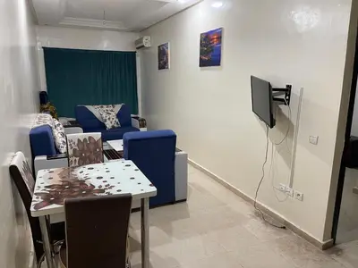 a living room with a table and a tv at Appartement 1er étage numéro 6 POUR FAMILLE in Marrakech