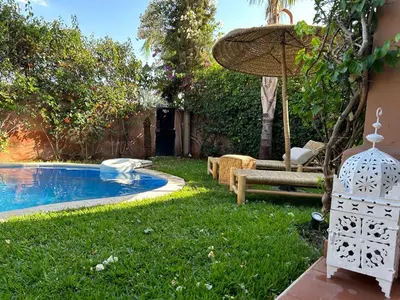 a backyard with a swimming pool and an umbrella at Villa Mezouza in Marrakech