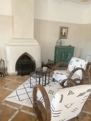 a living room with tables and chairs and a fireplace at Villa Mezouza in Marrakech