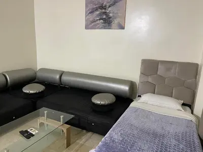 a living room with a black couch and a bed at Appartement 10 1èr étage. POUR FAMILLE in Marrakech