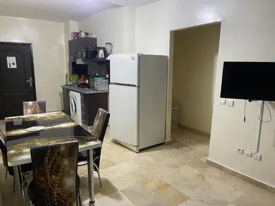 a kitchen with a table and a white refrigerator at Appartement 10 1èr étage. POUR FAMILLE in Marrakech