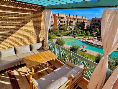 a balcony with a table and chairs and a pool at Chic Moroccan Vibes & Pool View - 2BR in Marrakech