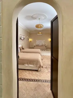 a bedroom with two beds and a hallway with a door at Riad Jolie in Marrakech