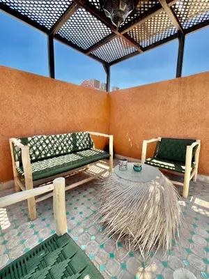 a patio with two benches and a table with a roof at Riad Jolie in Marrakech