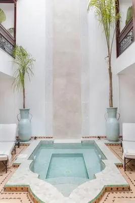 a swimming pool in a room with two palm trees at Riad Vivre - Design Boutique Riad in Marrakech in Marrakech
