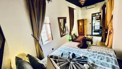 a bedroom with a bed with a cat sitting on it at Dar Najat in Marrakech