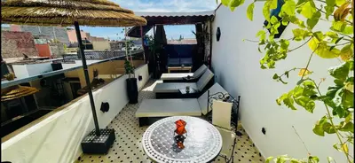 a balcony with a table and chairs and an umbrella at Dar Najat in Marrakech