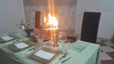 a table with a green table cloth with a fireplace at Riad sarsar airport in Marrakech