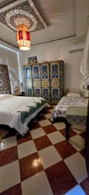 a bedroom with two beds and a checkered floor at Riad sarsar airport in Marrakech