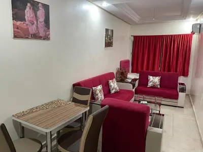 a living room with a red couch and a table at Appartement 18 3èm étage avec balcon ( POUR FAMILLE ) in Marrakech