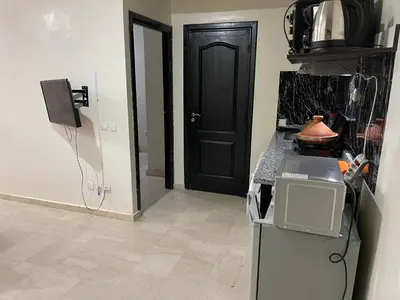 a kitchen with a refrigerator and a black door at Appartement 18 3èm étage avec balcon ( POUR FAMILLE ) in Marrakech