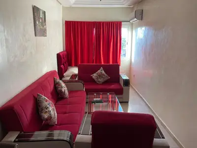 a living room with a red couch and a red curtain at Appartement 18 3èm étage avec balcon ( POUR FAMILLE ) in Marrakech
