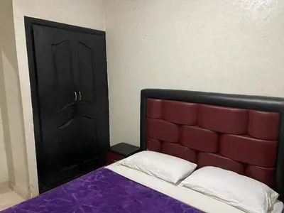 a bed with a red headboard and a black door at Appartement 20 3èm étage avec balcon ( POUR FAMILLE ) in Marrakech