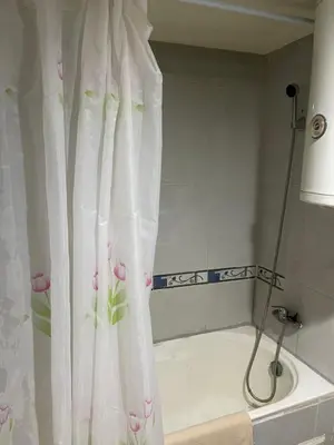 a bath tub with a shower curtain with pink flowers at Appartement 22 au 3ème étage ( POUR FAMILLE ) in Marrakech