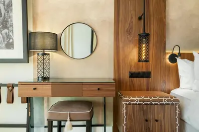 a bedroom with a bed and a desk with a mirror at Le Meridien N'fis in Marrakech