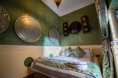 a bedroom with a bed with plates on the wall at Riad Ta'achchaqa in Marrakech
