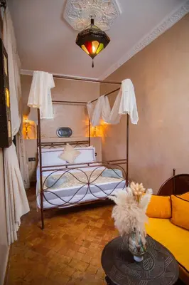 a bedroom with a bed and a table in a room at Riad Ta'achchaqa in Marrakech