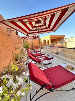 a group of red chairs under an umbrella on a balcony at Riad Shaden in Marrakech