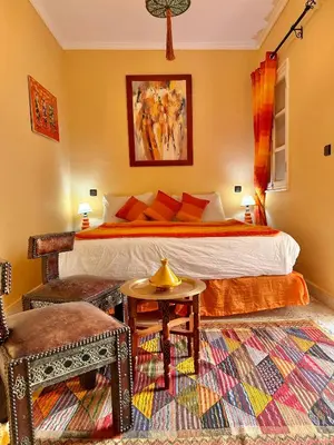 a bedroom with a bed and a table and a chair at Riad Shaden in Marrakech