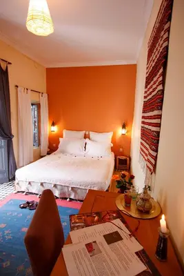 a bedroom with a bed and a desk and a table with a chair at Dar Touyir in Marrakech