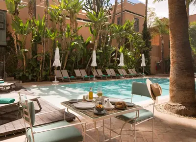 a pool with chairs and a table with food on it at Les Jardins De La Médina in Marrakech