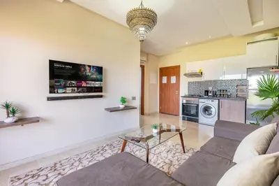 a living room with a couch and a kitchen at Perle Rare a Prestigia - Vue Sur Golf in Marrakech